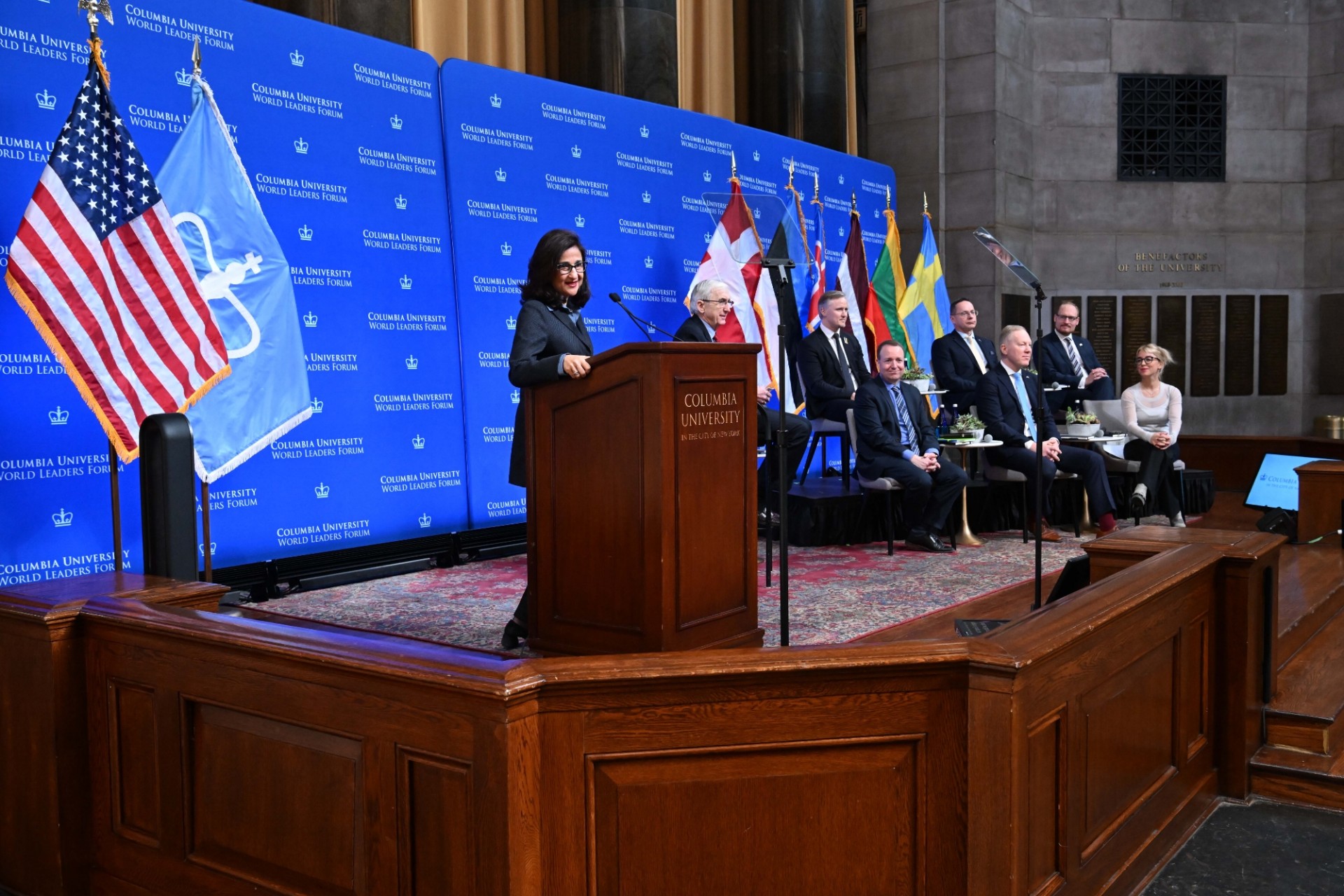 Columbia University President Minouche Shafik (left) speaking at the podium while Jenik Radon, Adjunct Professor of International and Public Affairs, and The Chairs of the Foreign Affairs Parliamentary Committees of Denmark, Estonia, Iceland, Latvia, Lithuania, and Sweden listen to opening remarks during the World Leaders Forum